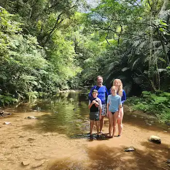 Family with two children standing in a jungle river surrounded by rainforest during an Ishigaki family tour