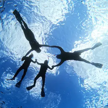 Underwater view of a family snorkeling together in Ishigaki Island, holding hands beneath the surface